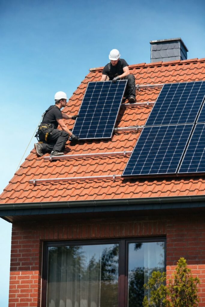 Solarteure montieren Photovoltaik-Module auf einem roten Ziegeldach